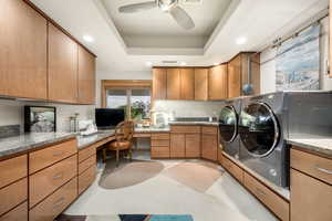 Laundry room featuring a raised ceiling, recessed lighting, ceiling fan, washing machine and clothes dryer, and cabinet space
