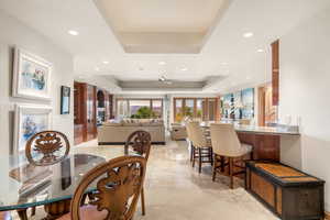 Dining area with a tray ceiling, a ceiling fan, recessed lighting, french doors, and arched walkways