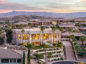 Back of property at dusk featuring stairs, a mountain view, a residential view, and stucco siding