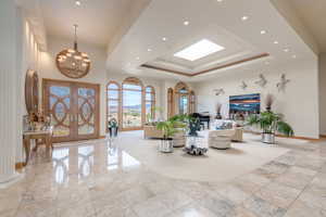 Living room featuring a tray ceiling, a chandelier, french doors, a high ceiling, and recessed lighting