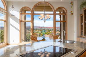 Kitchen view of dark stone counters, black electric cooktop, decorative light fixtures, and a chandelier