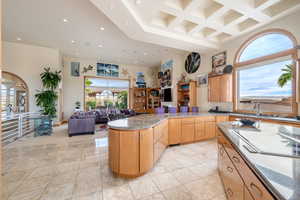Kitchen with a towering ceiling, coffered ceiling, dark stone counters, healthy amount of natural light, and white electric stovetop