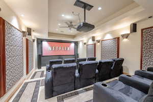 Cinema room featuring a raised ceiling, ceiling fan, and recessed lighting