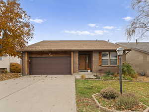 Ranch-style house with a shingled roof, driveway, and brick siding