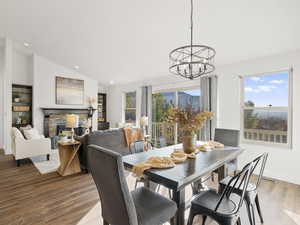 Dining room featuring vaulted ceiling, wood finished floors, a fireplace, and recessed lighting