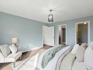 Bedroom with a spacious closet, wood finished floors, and ensuite bathroom