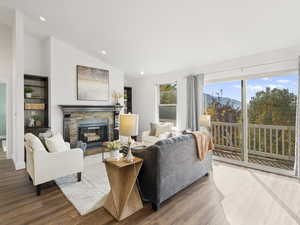 Living area with vaulted ceiling, wood finished floors, and a stone fireplace