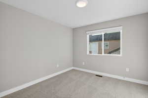 Carpeted spare room featuring baseboards