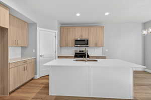 Kitchen featuring light stone countertops, tasteful backsplash, light wood-type flooring, stainless steel appliances, and recessed lighting
