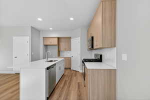 Kitchen with light stone countertops, modern cabinets, tasteful backsplash, stainless steel appliances, and light brown cabinetry