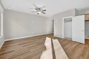 Unfurnished bedroom featuring light wood-type flooring, ceiling fan, and a closet