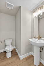 Half bath featuring a textured ceiling and light wood finished floors