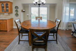 Dining room with dark wood-style flooring and a chandelier