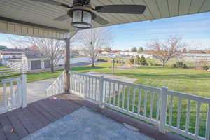 Wooden terrace featuring a lawn, ceiling fan, and a residential view