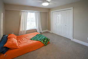 Carpeted bedroom with a ceiling fan and a closet