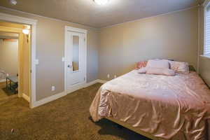 Bedroom with dark colored carpet and a textured ceiling