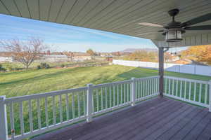 Wooden deck with a ceiling fan, a fenced backyard, a residential view, and a mountain view