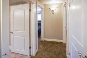 Corridor with dark colored carpet and baseboards