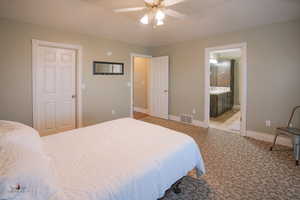 Carpeted bedroom featuring ceiling fan and ensuite bathroom