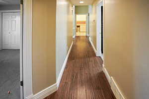 Hall with baseboards and dark wood-style flooring