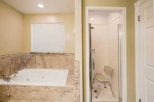 Bathroom with a jetted tub, a shower stall, and recessed lighting