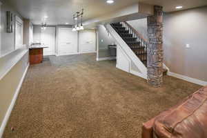 Finished below grade area with carpet, recessed lighting, a textured ceiling, and stairway