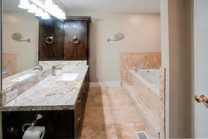 Bathroom with vanity, a garden tub, and light tile patterned floors