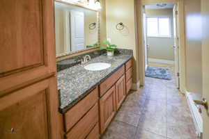 Bathroom with light tile patterned flooring, vanity, and a baseboard radiator