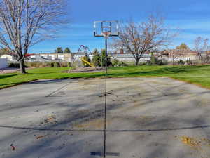 View of basketball court featuring basketball hoop, a playground, and a residential view