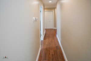 Hall with dark wood-style flooring and recessed lighting