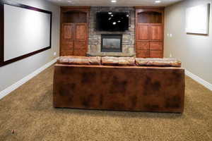 Carpeted home theater with a stone fireplace and recessed lighting