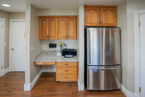 Kitchen featuring built in desk, light countertops, freestanding refrigerator, and brown cabinetry