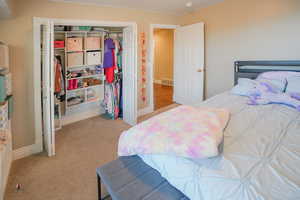 Bedroom with light carpet and a closet