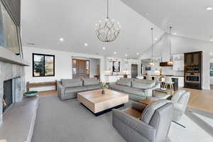 Living area with high vaulted ceiling, a stone fireplace, a chandelier, and recessed lighting