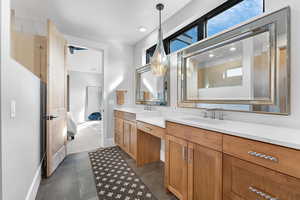 Ensuite bathroom with double vanity, recessed lighting, tiled shower, and dark tile patterned floors