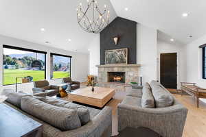 Living area featuring a fireplace, light wood-style floors, high vaulted ceiling, recessed lighting, and a chandelier