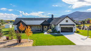 View of front facade with a metal roof, a front yard, concrete driveway, and a mountain view