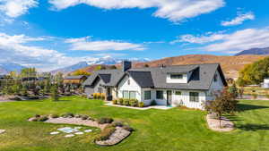 Rear view of property featuring a yard, a mountain view, a shingled roof, and board and batten siding