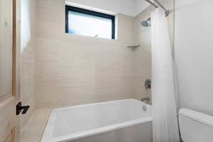 Full bath featuring shower / bath combo with shower curtain and toilet