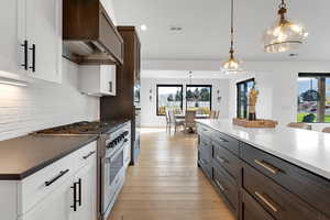 Kitchen featuring appliances with stainless steel finishes, hanging light fixtures, light wood-type flooring, recessed lighting, and white cabinetry