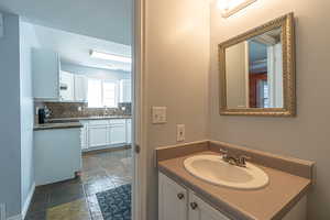 Bathroom featuring vanity, decorative backsplash, stone tile floors, and a textured ceiling