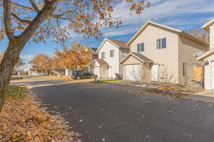 View of front of house featuring a residential view, a garage, driveway, and roof with shingles