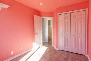 Unfurnished bedroom with wood finished floors and a closet