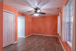 Unfurnished room featuring dark wood-type flooring, ceiling fan, and a textured ceiling