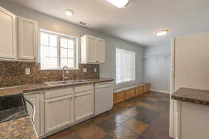 Kitchen with decorative backsplash, tile countertops, white appliances, and stone tile flooring