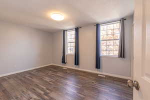 Spare room featuring a textured ceiling and dark wood-type flooring