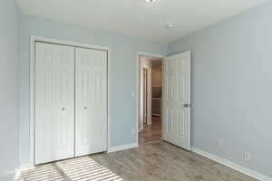 Unfurnished bedroom with wood finished floors and a closet