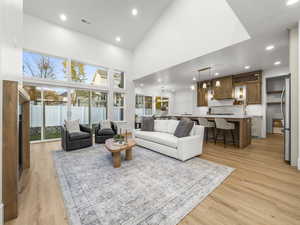 Living area with high vaulted ceiling, recessed lighting, light wood-type flooring, and a chandelier