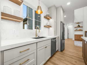 Kitchen with open shelves, light stone counters, light wood-type flooring, decorative backsplash, and recessed lighting