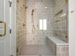 Bathroom featuring a shower stall and tile walls